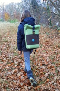 Ein Kind, dargestellt von hinten in herbstlicher Landschaft , trägt einen Wollfilz-Rucksack 